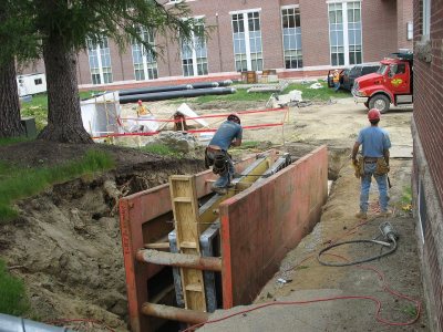 Workers set a "trench box" where a retaining wall is being built next to Hedge. (Doug Hubley/Bates College)