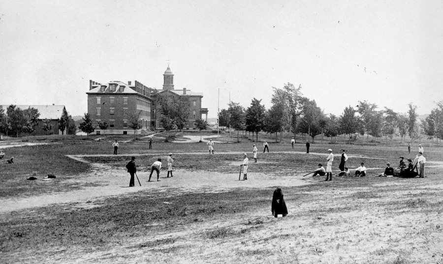 Ballplayers play baseball on the old Rand Field in 1882, as viewed from the base of Mount David. Parker and Hathorn halls are beyond left field. The original Bates gymnasium is at far left. (Muskie Archives and Special Collections LIbrary)