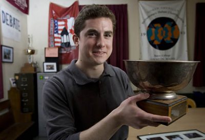 Bates debater Geoff Shaughnessy â09 of Hanover, N.H., poses in the Brooks Quimby Debate Council's storied practice room on the second floor of Pettigrew Hall. The trophy bowl he holds is a first place award for Bates from a tournament held at MIT in 1981, five years before Shaughnessy's birth. The croquet mallet he holds sometimes substitutes for a gavel during team practices. The traditional mallets have disappeared.