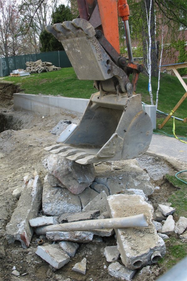 Rocks, concrete, and pipes mined from Hedge Hall's basement, shown with the excavator that will load it into a truck for disposal. (Doug hubley/Bates College)