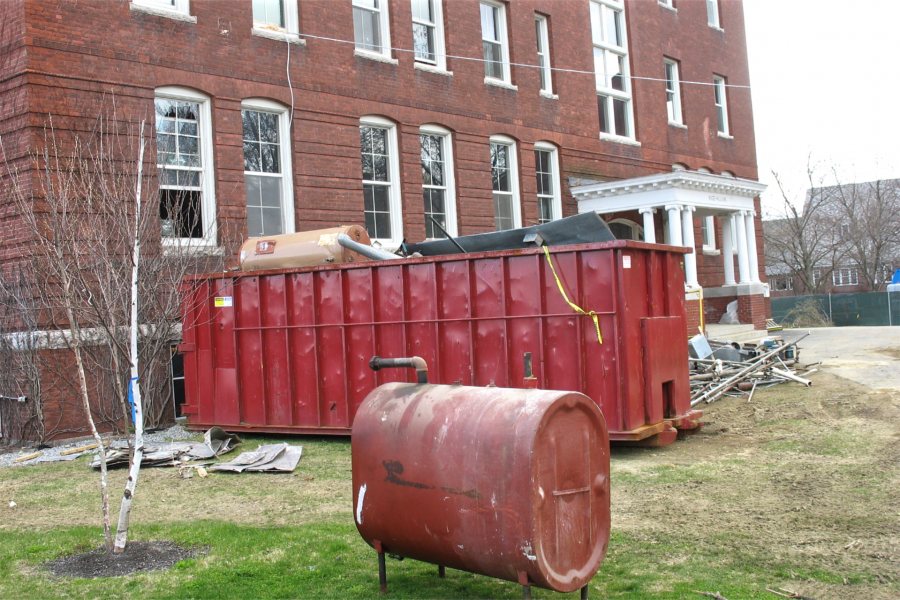 With a fuel oil tank still up on all fours and bound for re-use, a Dumpster is filled with less desirable debris from Roger Williams Hall. (Doug Hubley/Bates College)