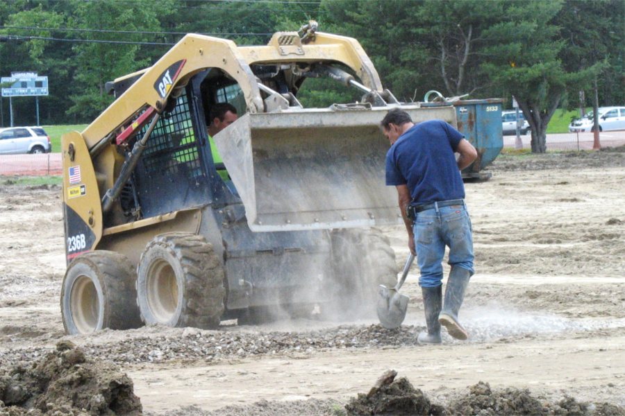 A laborer spreads gravel just dumped on Garcelon Field by the front-end loader. (Doug Hubley/Bates College)