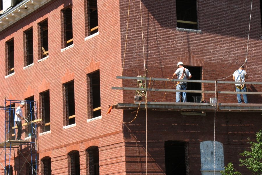 Workers on staging at Roger Williams Hall include two masons repointing the bricks. (Doug Hubley/Bates College)