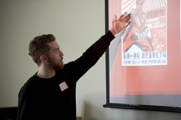 Clay Baldo '13 explains a Chinese political poster during the Mount David Summit. Photograph by Michael Bradley/Bates College College.