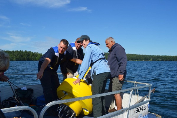 Lake Auburn Watershed Protection staffers and environmental studies professor Holly Ewing (pale blue jacket) prepare to place a sensor buoy in  Lake Andrews. Kate Paladin '15/Bates College.