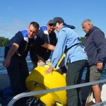 Lake Auburn Watershed Protection staffers and environmental studies professor Holly Ewing (pale blue jacket) prepare to place a sensor buoy in  Lake Andrews. Kate Paladin '15/Bates College.