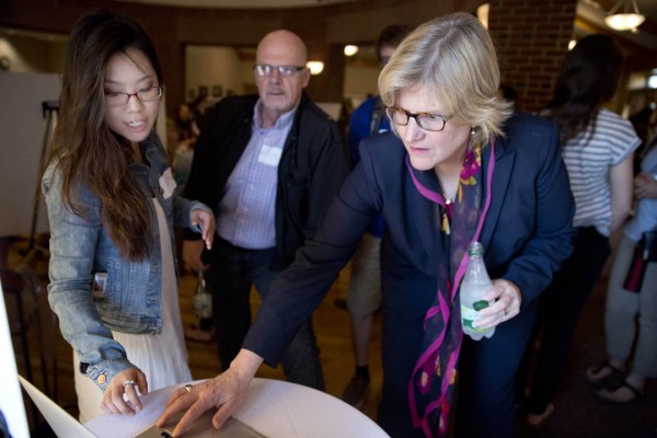 Hyo Sun Hong '16 of Montclair, Calif., who studied graphic design during Short Term under Brandy Gibbs-Riley '96, explains to President Spencer and Professor of Russian Dennis Browne how she and her classmates developed a logo for the annual Harvest Dinner. (Phyllis Graber Jensen/Bates College)