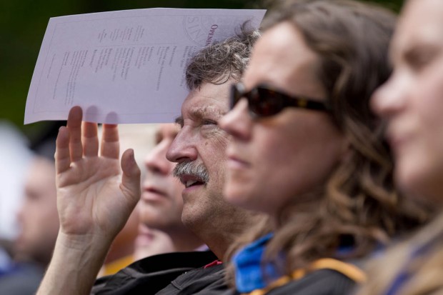 Mathematics professor Chip Ross shields himself from the early September sun during a warm and muggy Convocation 2014. (Phyllis Graber Jensen/Bates College)