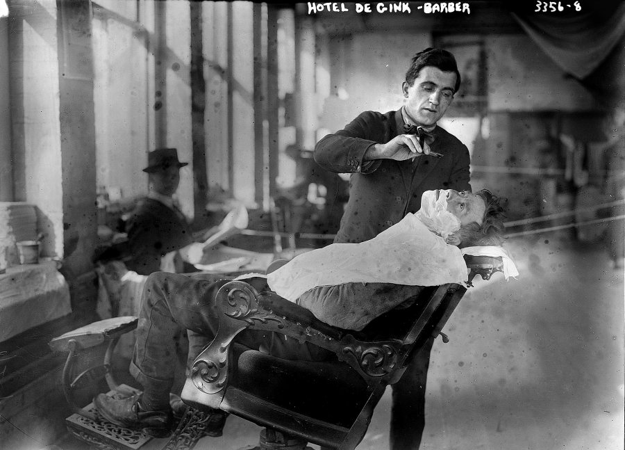 A barber shaves a customer at Hotel de Gink, a hotel for the homeless in New York City, in 1915. Herzig's book notes that "the advent of the bathroom facilitated shaving’s passage from the public barber shop to the private space of the home.... he labors of hair removal were newly individualized and concealed."  