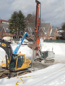 With Muskie Archives in the background, a loader feeds aggregrate to the Helical Drilling rig implanting Geopiers on Jan. 9, 2015. The same rig without the aggregate hopper is used to make GeoConcrete columns. (Doug Hubley/Bates College)