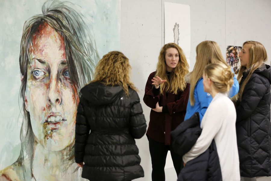 Student work in the visual, literary and performing arts takes center stage at Bates' annual Arts Crawl. In this 2015 image, studio art major Hannah McGrath '15 of Longmeadow, Mass., explains the process used by a fellow member of her thesis group, Ayse Ikizler '15 of Nashville, to create the painting seen at left. (Max Huang '18 for Bates College)