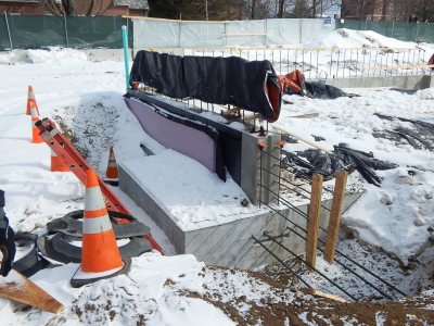 A wall foundation section sits on a spread footing at 65 Campus Ave. The black materials on the side of the concrete form are for moistureproofing. (Doug Hubley/Bates College)