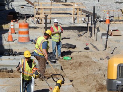 Van Terrell, S.W. Cole Engineering field technician (third from left), prepares to use the the green gizmo at his feet to check the soil density in the 65 Campus Ave. cellar hole on April 14, 2015. (Doug Hubley/Bates College)