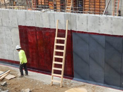 A waterproofing technician steps away from an exterior basement wall at 65 Campus Ave. on March 26, 2015. (Doug Hubley/Bates College)