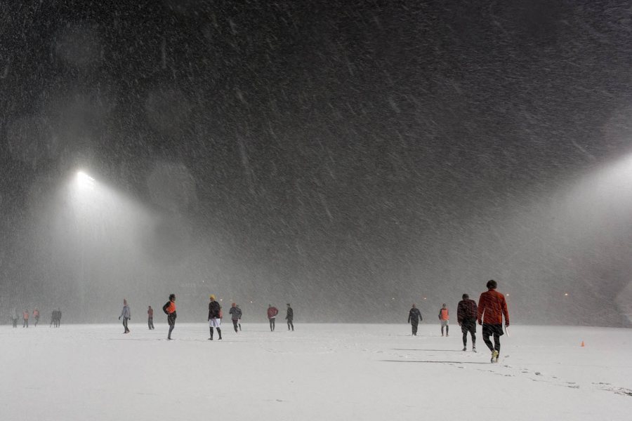 Seemingly oblivious to the early April snow, ultimate frisbee players practice on Garcelon Field. (Josh Kuckens/Bates College)