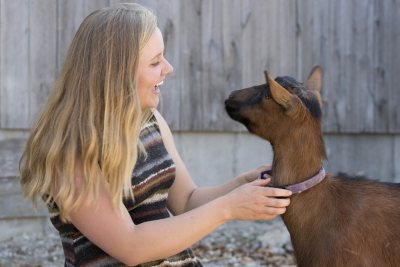 Watson Fellow Caroline Caldwell '15 greets a goat at Nezinscot Farm. (Phyllis Graber Jensen/Bates College)