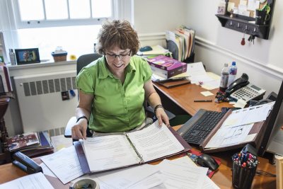 Claire Schmoll, executive assistant to President Spencer, prepares the formularies -- compilations of all the Commencement speeches -- in her Lane Hall office. (Josh Kuckens/Bates College)