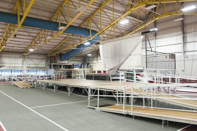 The fallback stage: In case of inclement weather, a second Commencement stage is set up in Merrill Gymnasium. (Josh Kuckens/Bates College)