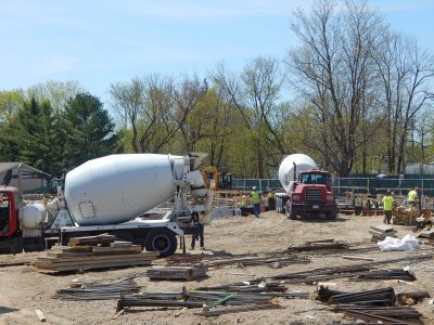 Concrete mixers ready to place foundation footings for the 55 Campus Ave. student residence on May 7, 2015. (Doug Hubley/Bates College)