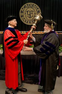 Professor of Sociology Sawyer Sylvester, who as senior member of the faculty was the longtime bearer of the college mace at ceremonial events, handed the mace over to his successor, Charles Franklin Phillips Professor of Economics Michael Murray at Commencement 2015. (Phyllis Graber Jensen/Bates College)