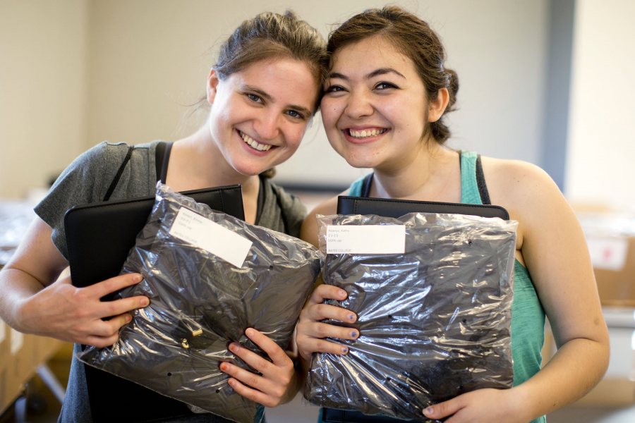 Passing another marker on the road to Sunday's Commencement, seniors and close friends Emma Korein (left), a psychology and French major from Rydal, Pa., and Kathy Polanco, an environmental studies and theater major from Los Angeles, pose for a portrait as they pick up their caps and gowns in Commons on May 27.  ‪(Phyllis Graber Jensen/Bates College)