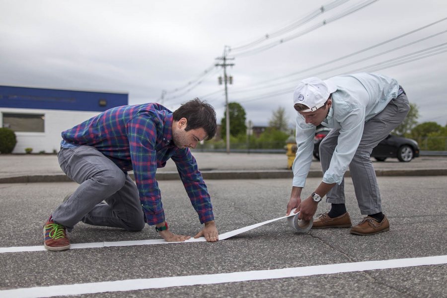 Matthew Winter '18 of New York City and Brendan Yucel '18 of Boston lay down lines for a demonstration bike lane on Oxford Street in Lewiston on May 20. They're students in an urban planning Short Term course taught by Mike Lydon '04. (Josh Kuckens/Bates College)