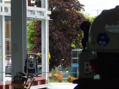 The Trimble "total station," fastened to a beam at left, guides the surveyor (back to camera) as he marks utilities sites at 65 Campus Ave. on June 3, 2015. (Doug Hubley/Bates College)  