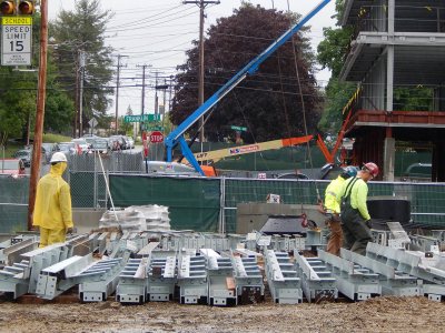 Holding onto the ends of cables attached to the construction crane, steelworkers look for the next pieces to be lifted into place at 55 Campus Ave. on June 2, 2015, the first day of steel work. (Doug Hubley/Bates College)