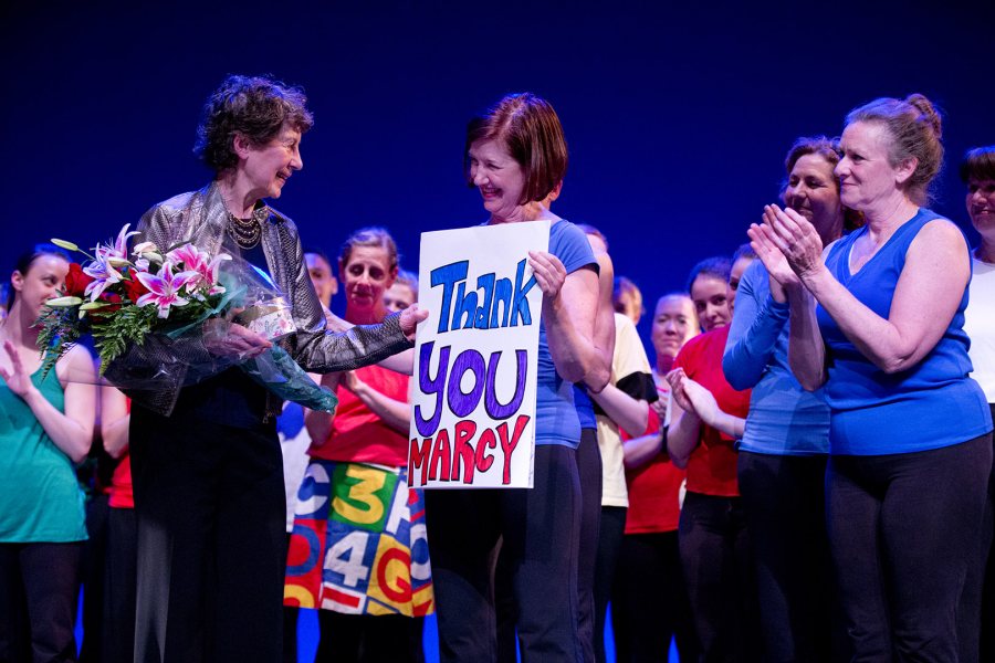 Geri FitzGerald '75 holds a thank-you sign for Marcy Plavin at the conclusion of the 2015 dance reunion concert in Schaeffer Theatre. (Phyllis Graber Jensen/Bates College)