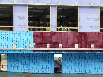 A bouquet of structural wall treatments: lavender gypsum board, Dodger blue vapor barrier and the burgundy adhesive that holds them together. 65 Campus Ave. on July 24, 2015. (Doug Hubley/Bates College)