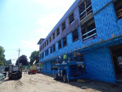 Turning blue on a hot day: Insulation technicians apply a stick-on blue vapor barrier to the north wall of 65 Campus Ave. on July 28, 2015. (Doug Hubley/Bates College)