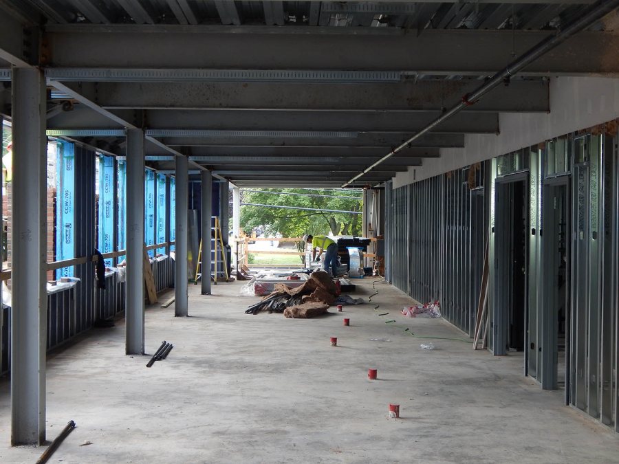 A wall framer at work on the second floor of 65 Campus Ave. on Aug. 26, 2015. The enclosed space at right is part of the building core. Visible beyond are the grounds of Lewiston Middle School. (Doug Hubley/Bates College)