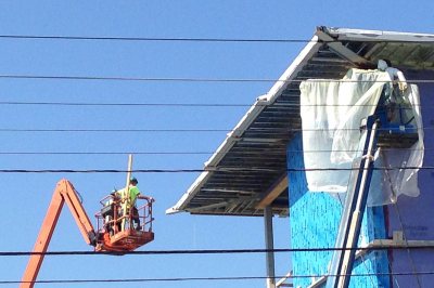 Technicians on two lifts working on the roof of No. 65 Campus Ave. on Sept. 16, 2015. (Doug Hubley/Bates College)