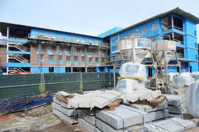 With the new student residence at 65 Campus Ave. in the background on Sept. 21, 2015, granite and pre-cast concrete forms await their turn with the masons. The conical bins hold mortar. (Doug Hubley/Bates College)