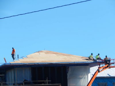 Industrial Roofing Corp. technicians roll a fabric barrier out over oriented-strand panels at 65 Campus Ave. on Oct. 16 [checkit], 2015. (Doug Hubley/Bates College)