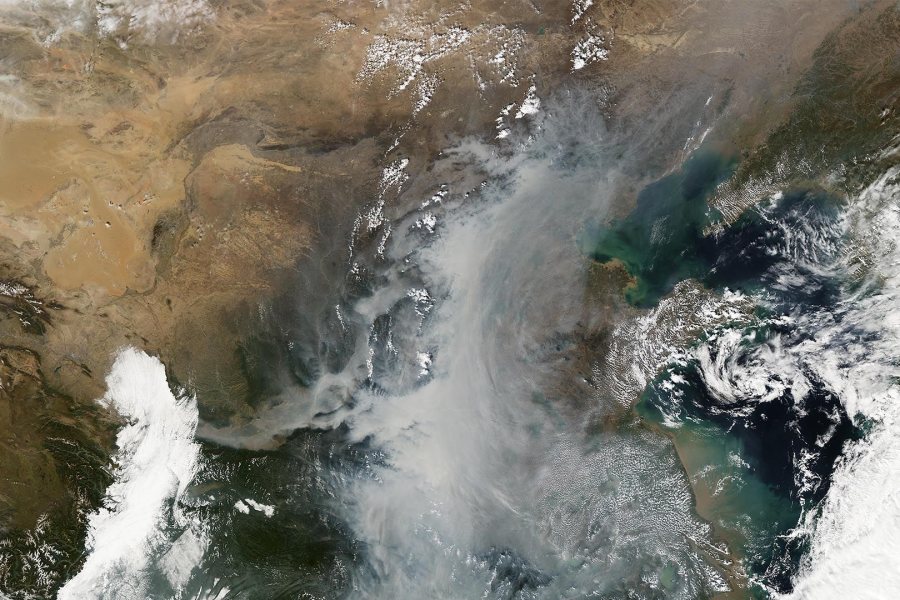 The milky white and gray at center of the image shows smog and fog event over China. The brighter whites at left and right are clouds. (NASA Earth Observatory)
