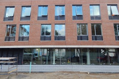 Storefront glass on the ground floor of 65 Campus Ave. reveals workers inside the building on Oct. 30, 2015. (Doug Hubley/Bates College)