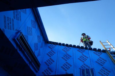A roofing technician seen from the mechanical well at 55 Campus Ave. on Dec. 1, 2015. (Doug Hubley/Bates College) 