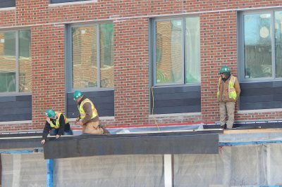 Technicians for Industrial Roofing Corp. install a weatherproof membrane on a shallow overhang at 65 Campus Ave. on Jan. 7, 2016. (Doug Hubley/Bates College)