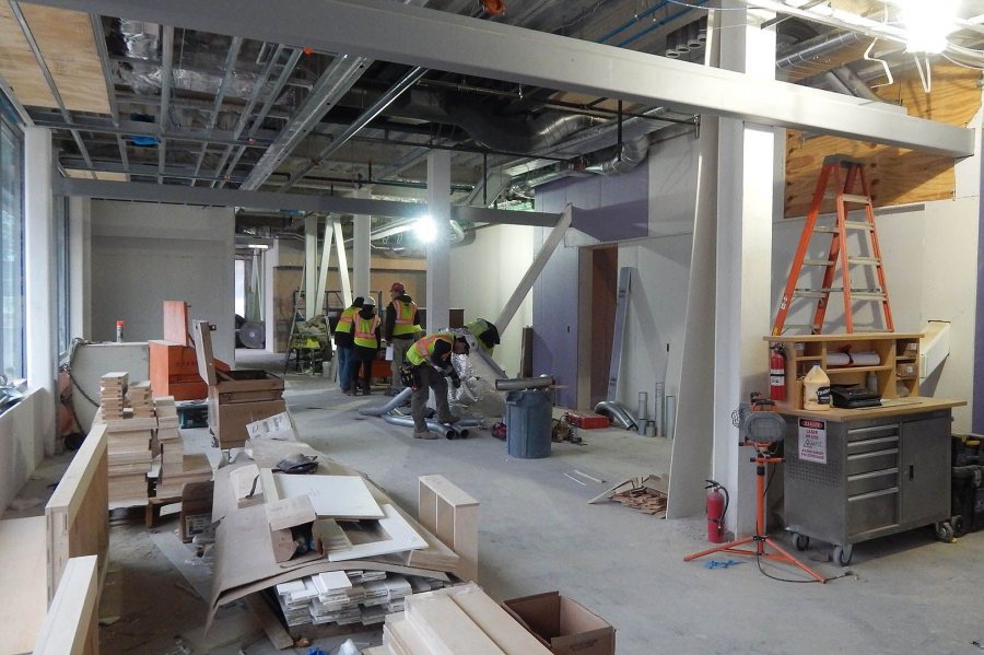 In store for Bates: While architects from the Ann Beha firm consult with a Consigli Construction executive, a ventilation technician cuts a piece of ductwork on Jan. 12, 2016. The Bates College Store will occupy this space in 55 Campus Ave. (Doug Hubley/Bates College)