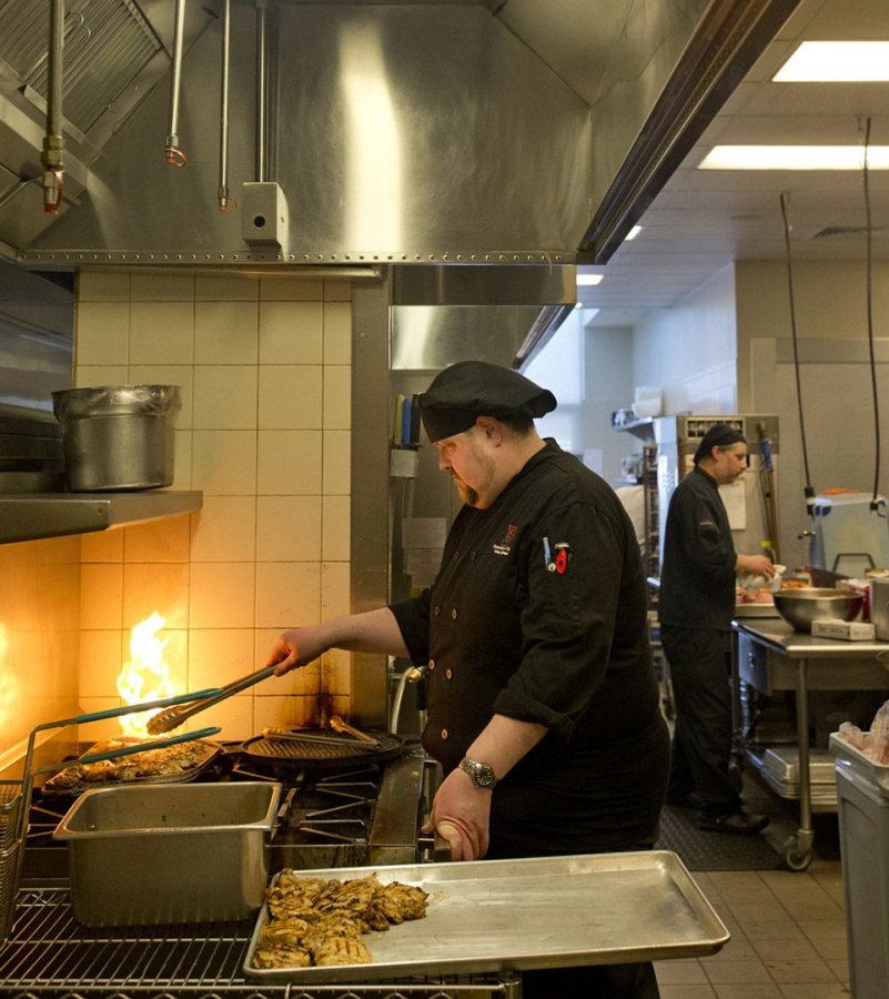 Executive chef Owen Keene grills chicken under an Intelli-Hood in the kitchen at Commons. One sensor is attached to the hood and looks like a pencil sharpener. (Phyllis Graber Jensen/Bates College)