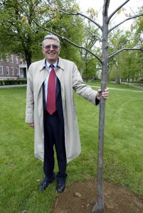 In 2003, Jim Carignan '61 stands next to an oak planted on campus honor his retirement as dean of the college. (Phyllis Graber Jensen/Bates College)