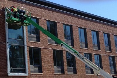 Construction workers on lifts, like this window technician photographed at 55 Campus Ave. on April 15, were a dwindling breed at Bates during spring 2015. (Doug Hubley/Bates College)