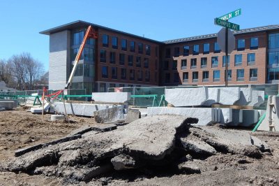 The old and the new: Remnants of an asphalt sidewalk are heaped in front of new granite curbs on April 27, 2015. In the background is 55 Campus Ave. (Doug Hubley/Bates College)