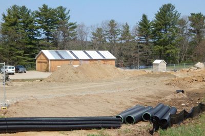 Bates' 1988 pole-barn-style boathouse awaits its fate. Drain pipes and stockpiled soil will be used for the construction of the new facility. At far left is Campus Construction Update's radar-equipped van. (Doug Hubley/Bates College) 