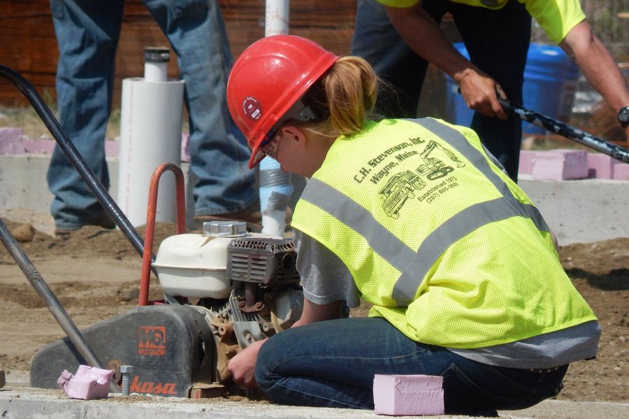 In preparation for placing the Bates boathouse foundation slab, an employee of construction firm C.H. Stevenson adjusts a plate compactor. (Doug Hubley/Bates College) 