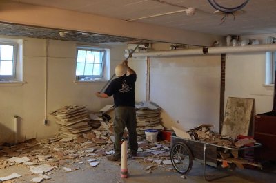 A worker scrapes tiles off the ceiling in the basement of Smith Hall on June 8, 2016. (Doug Hubley/Bates College) 