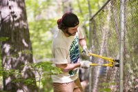 George Fiske '19 of West Hartford, Conn., cuts wire that holds derelict chain-link fencing to posts on Mount David during the EcoService Day project on May 21. (Phyllis Graber Jensen/Bates College)