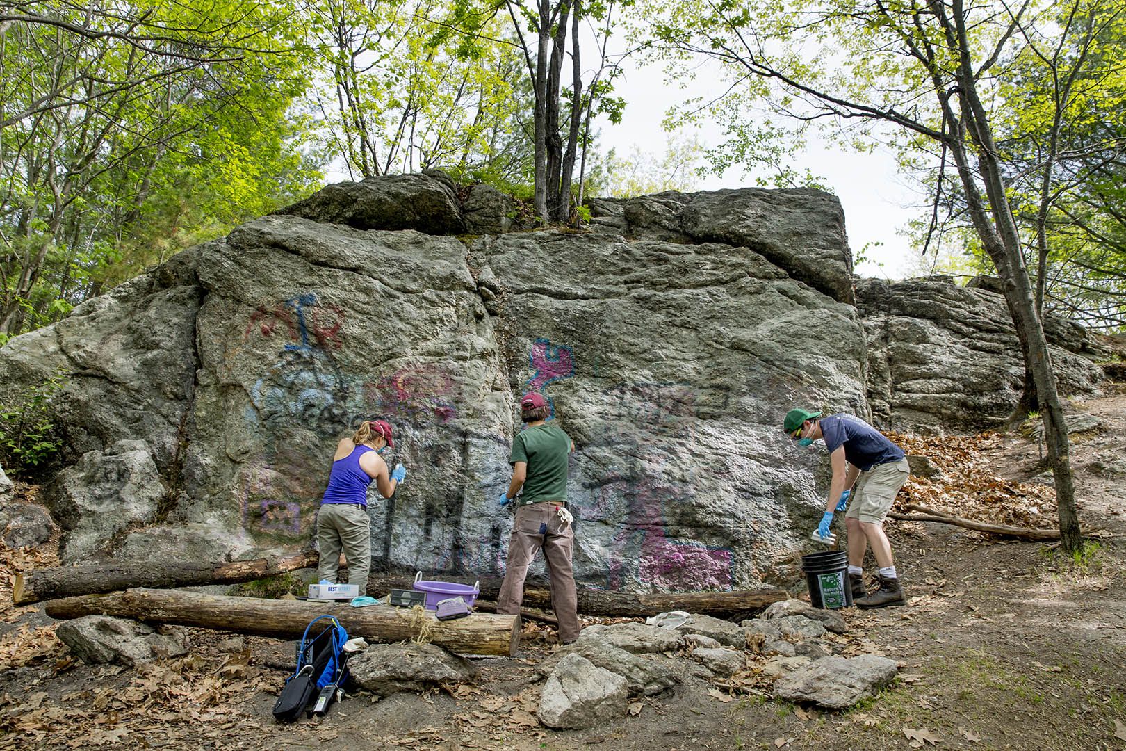 From left, Katie Stevenson '17 of Ewing, N.J., Bates sustainability manager Tom Twist, and Doug McNab '18 of Hyde Park, Mass., remove graffiti from exposed rock about half-way up the trail to the summit of Mount David during the EcoService Day project on May 21. (Phyllis Graber Jensen/Bates College)

