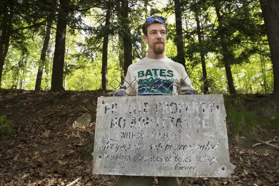 Dana Cohen-Kaplan '16 holds an old sign that reads, "Private Property: No Admittance Without Permission, Trespassers will be prosecuted, President and Trustees of Bates College, Owner." (Phyllis Graber Jensen/Bates College)